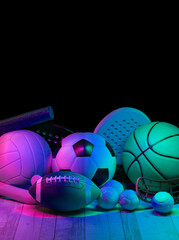 Sports equipment, rackets and balls on hardwood court floor with neon light background. Vertical...