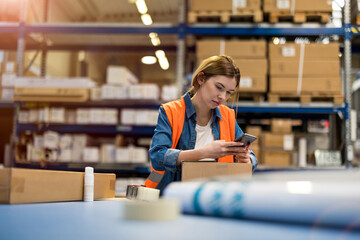 Female warehouse worker using mobile phone
- 496185872
