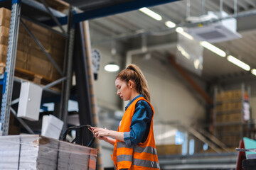 Woman with tablet in factory storehouse checking location of goods