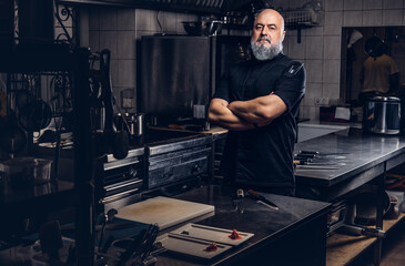 Fototapeta na wymiar Muscular old man chef with gray beard and crossed arms