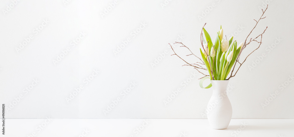 Wall mural White spring tulips in a vase on a white table. Mock up for displaying works