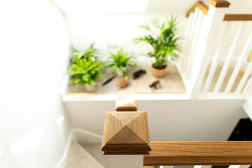 Shallow focus of the hard wood texture of a 2nd floor bannister post of a newly installed loft conversion. A carpeted shelf is seen, showing plants and ornaments.
