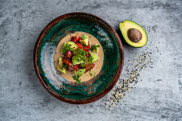 Salad with avocado, lettuce, tomato and flax seeds on gray background.Close up