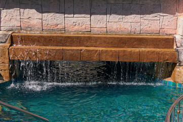 Water is passing over fountain and drooping into pool.
