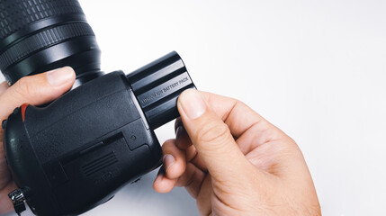 Photographer hand installing lithium ion battery of digital DSLR cameras,isolated on white...