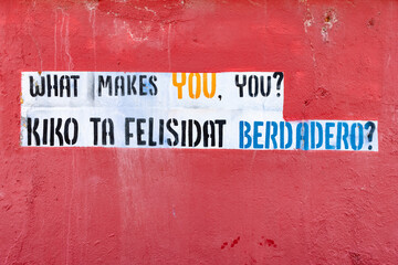 artwork with the question "what makes you, you?" on a red wall in Willemstad, Curacao