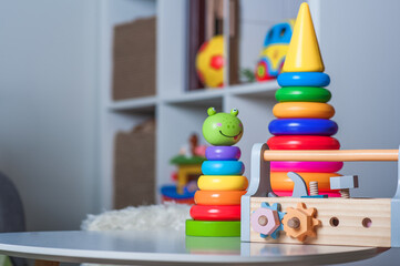 Handsome toddler boy playing with educational wooden and plastic toys in children's room..