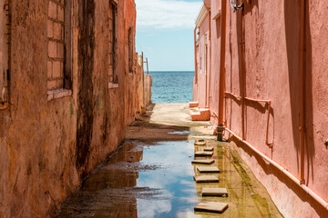 View to the Caribbean Sea through weathered red painted houses in Willemstad, Curacao