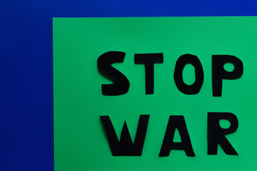 Top view of stop war paper lettering on green and blue background.