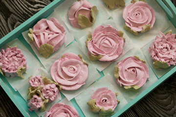 Homemade marshmallows of different shapes and colors. Zephyr flowers. On pine boards.