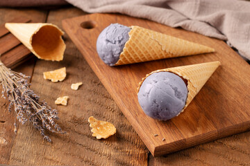 Provence. Natural lavender ice cream in waffle cones on a wooden background. Homemade dessert. Rustic style. Bouquet of lavender flowers. Top view,