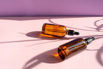 Still life of cosmetic products. Blank, isolated on a powdery pink and lilac background to accommodate your design with sun shadows.