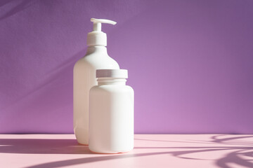 white cosmetic jars on a lilac-pink background with sun shadows. template for cosmetics.