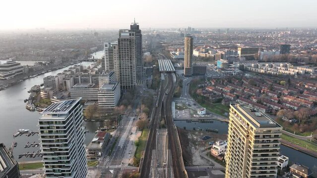 Amsterdamn Amstel urban city aerial drone view transportation and urban residential construction towers. Infrastructure train station business buildings and skyline. Water canal.