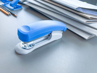 Photo of blue stapler put on the table in office, stapler is a device used in schools or offices - obrazy, fototapety, plakaty