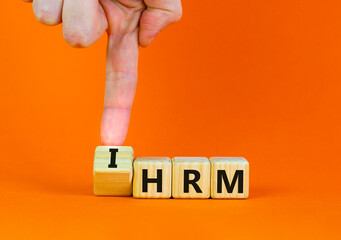 IHRM, international human resource management HRM symbol. Words IHRM, international human resource management on cubes on a orange background. Businessman hand. Business, IHRM HRM concept. Copy space.