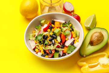 Bowl of Mexican vegetable salad with black beans, radish and ingredients on yellow background