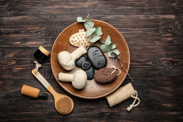 Tray with bathing supplies, spa stones and herbal bags on wooden background