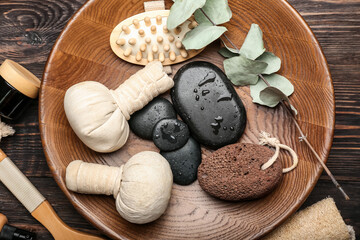 Tray with bathing supplies, spa stones and herbal bags on wooden background