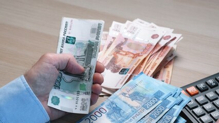 Men's hands count money, the currency is the Russian ruble. Concepts of finance and wealth. Banknotes of 1000 rubles in the hands of men. Investments, saving money.
