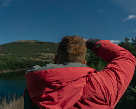 hombre haciendo fotos a un paisaje natural, chico fotografiando la naturaleza, chico con abrigo rojo fotograf&iacute;a el entorno natural de un bosque 