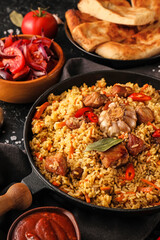 Frying pan with tasty Asian pilaf on table