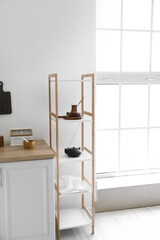 Shelf unit with kitchenware near white wall