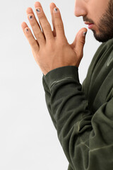 Young man with stylish manicure on light background, closeup