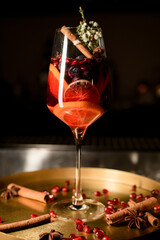 Crystal glass with alcoholic cocktail decorated with flower branch and cinnamon stick