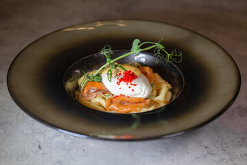 Pancake with salmon and cheese. Serving a dish in a plate on a gray background