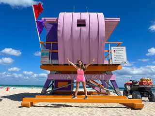 Brazilian woman in pink, in a purple lifeguard house, in Miami Beach