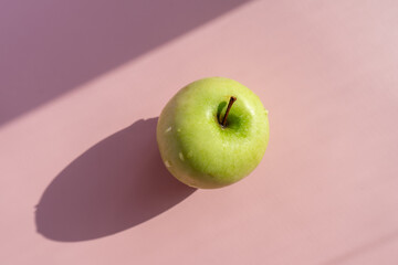 green apple on a delicate lilac-pink background. place for copywriting.