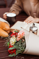 French clothing style, street fashion. A beautiful girl in a cardigan, red beret, and glasses walks through the old city and sits in a cafe. Spring mood and vibes