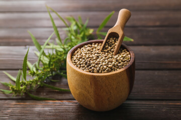 Bowl and scoop with hemp seeds on wooden background