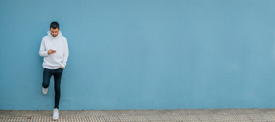 Fototapeta premium young man with mobile phone on the street wall