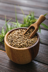 Bowl and scoop with hemp seeds on wooden background