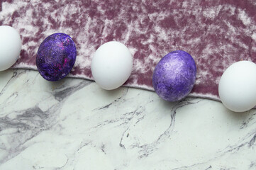 Obraz premium Alternation of white and purple eggs laid out in a line on a marble and pink background. Easter card with a place for the text.