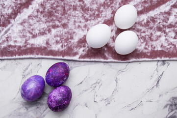White and purple eggs lie opposite each other on a separated background. A postcard for Easter with a place for the text.