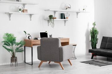 Comfortable workplace and houseplants in stylish room interior
