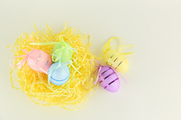 Three colored eggs lie in the nest on a white background with copyspace view from the side of Von...