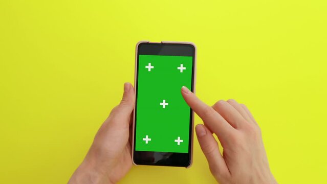 Scrolling gesture on Green Mock-up Screen Chroma Key. Surfing internet, social media or online shop - internet, communications concept. Copy space for videp product placement. Phone on creative yellow