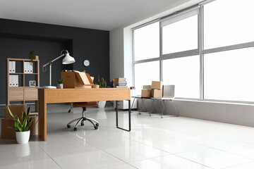 Cardboard boxes with belongings and furniture in interior of office on moving day