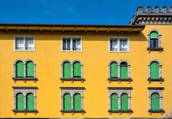 A well kept old yellow building with green shutters