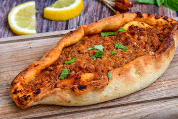  Traditional Turkish cuisine. Baked Pide dish with minced  beef, tomatoes and cheese on  wooden background.  Turkish pizza pide