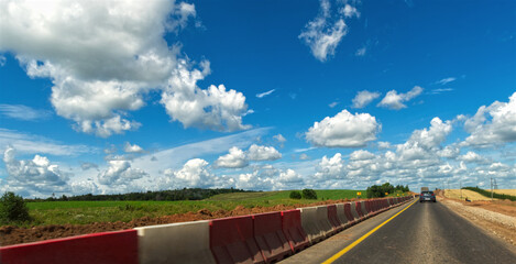 The road goes to the horizon against the backdrop of a beautiful sky with clouds.