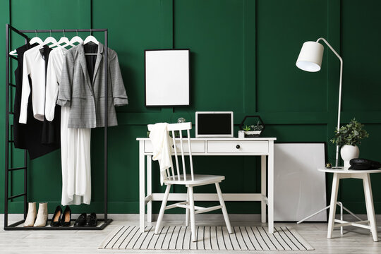 Interior of modern room with workplace, rack and blank photo frame on green wall