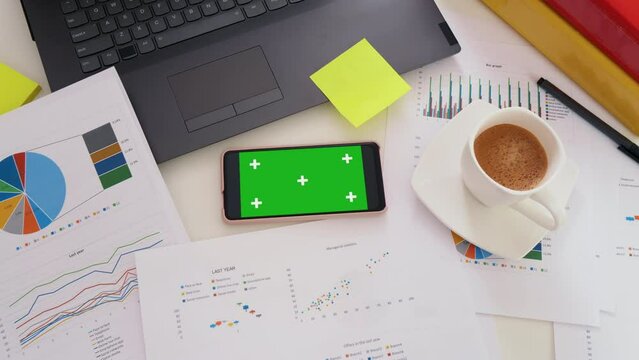 Smartphone with green screen, application for business. Office table workspace