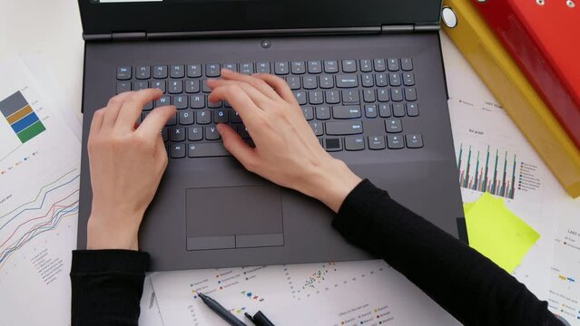 Female using laptop computer on office table background. Typing on laptop keyboard. Top view. Business and finance concept.