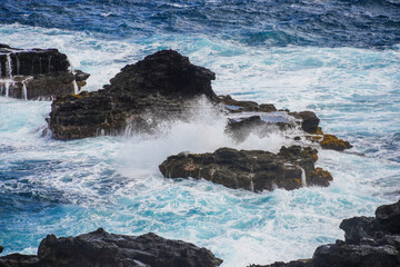 Waves crashing on sea rocks in the Pacific Ocean along the Kahekili Highway in West Maui, Hawaii,...