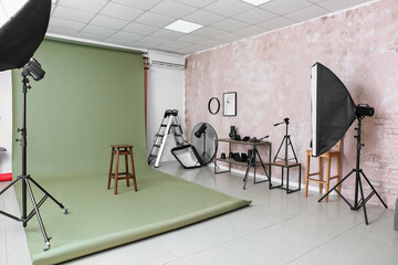 Lighting equipment, green cyclorama and stool in modern photo studio